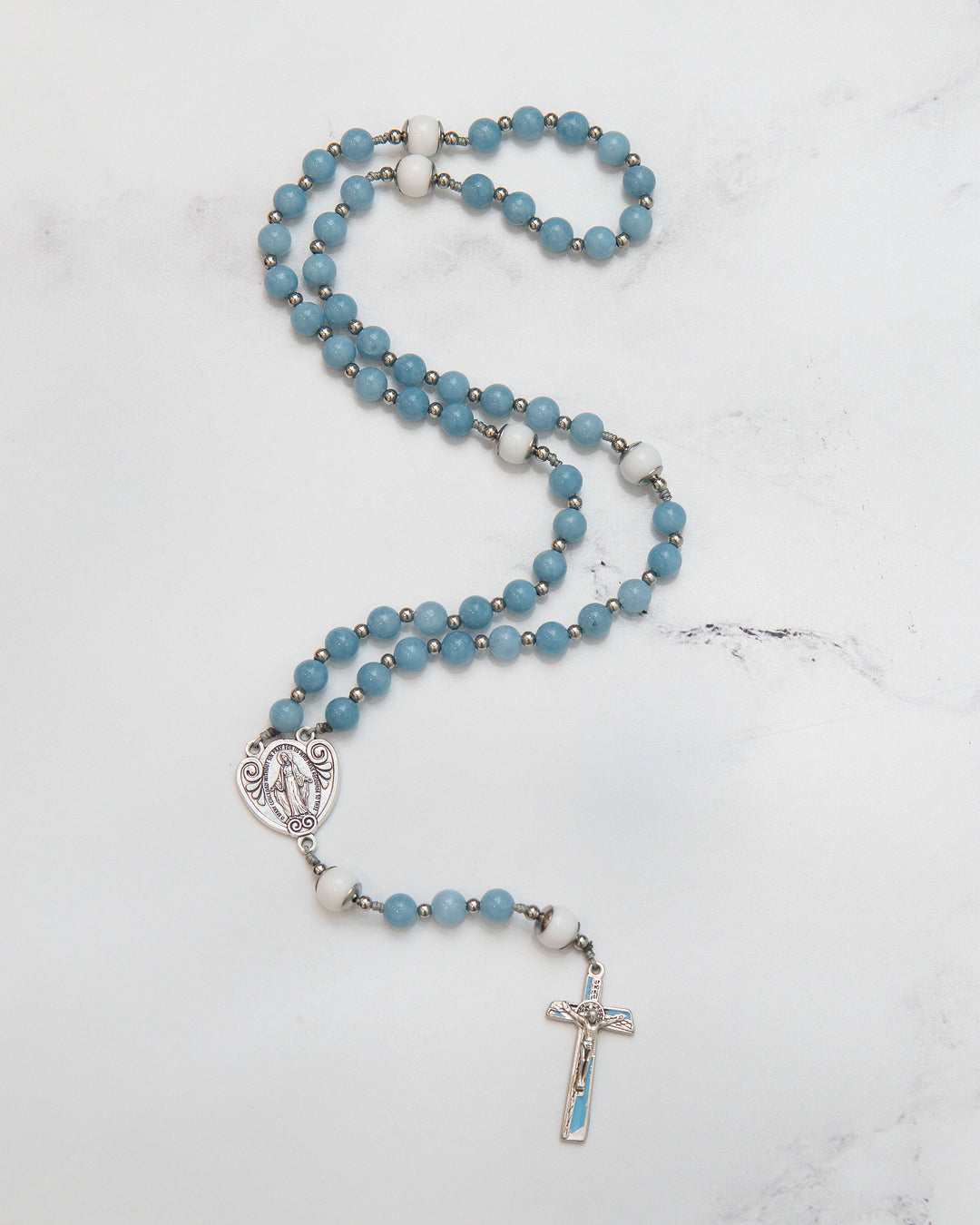 The Angelite Rosary laid flat on marble surface