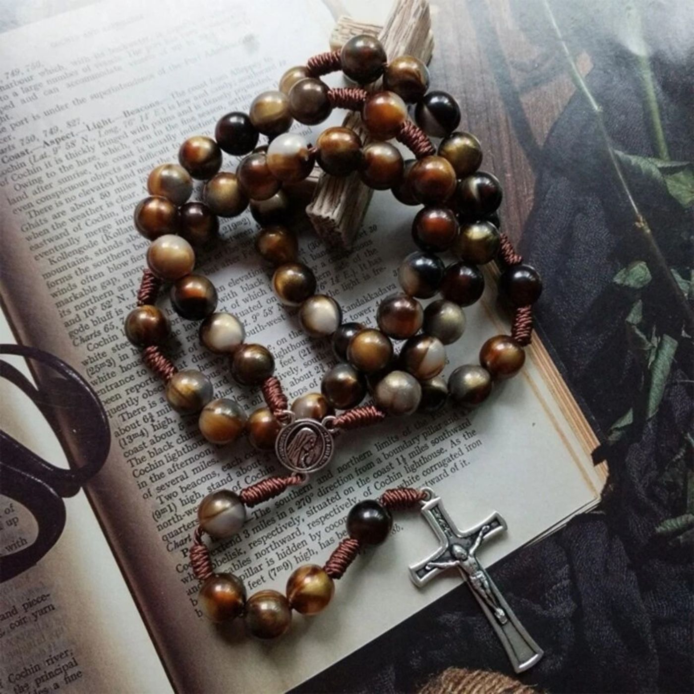 Handcrafted wooden rosary with a silver crucifix displayed on an open book. Visit www.blessedcatholic.com for handcrafted rosaries, necklaces, bracelets, and sacred accessories.