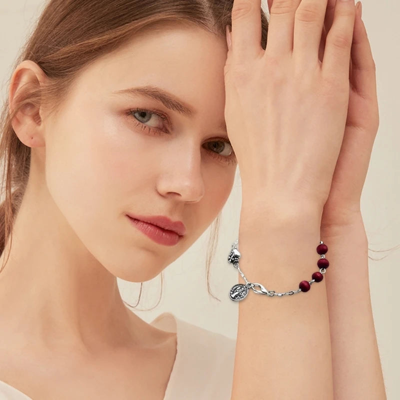 Vintage-style bracelet featuring dark red scented wooden beads and a silver St. Mary pendant on a chain, perfect for spiritual expression and fashion.