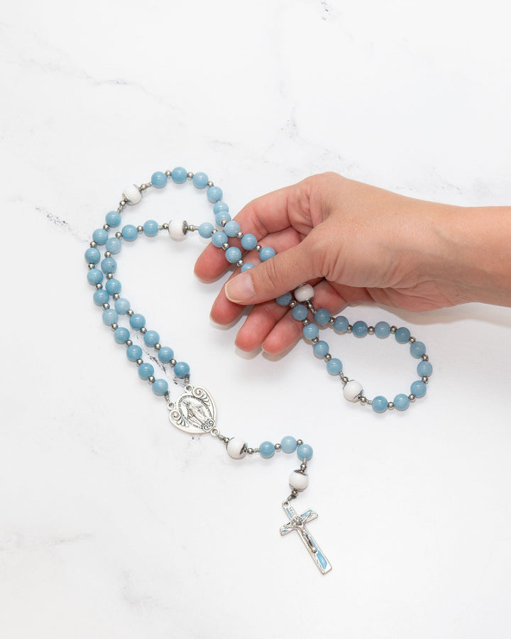 Hand holding The Angelite Rosary on marble surface
